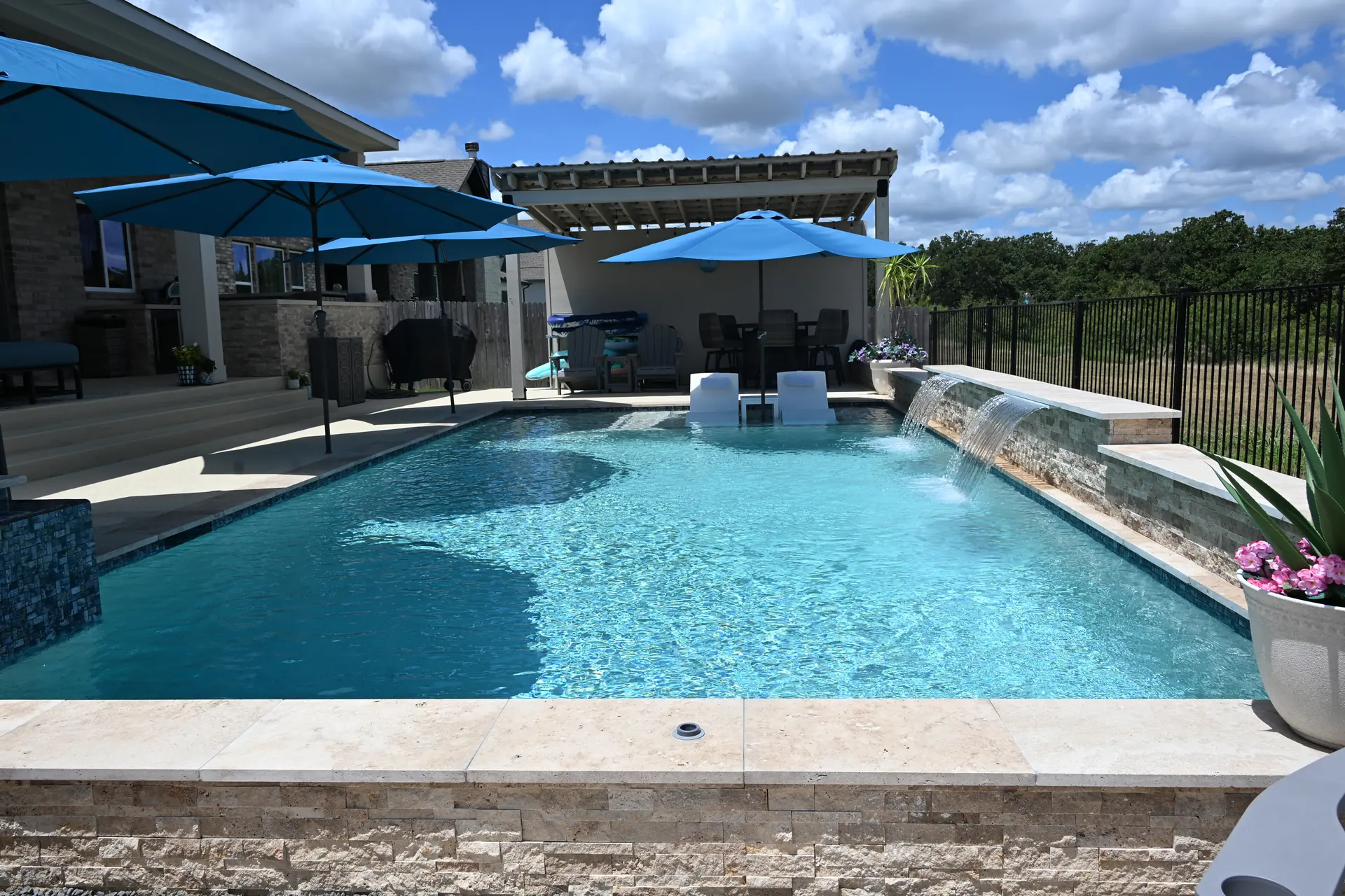 Custom gunite pool with a raised spa, pergola and outdoor kitchen in a Central Texas backyard