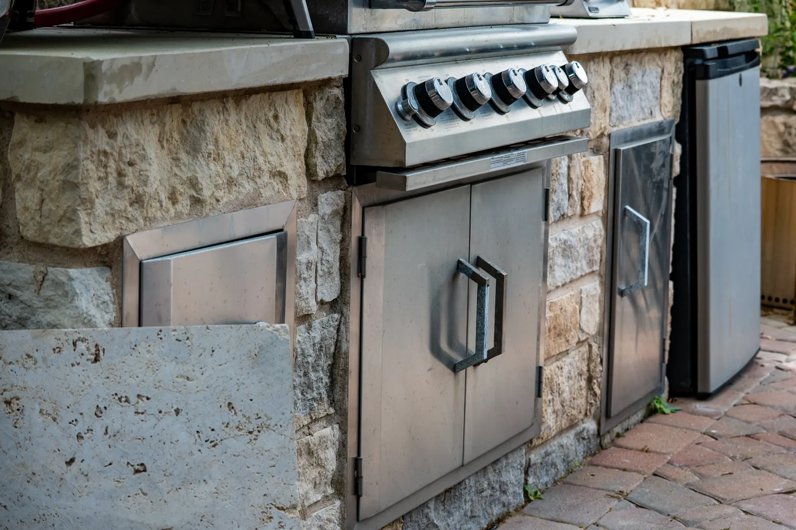 Close view of a built-in stainless grill set in limestone