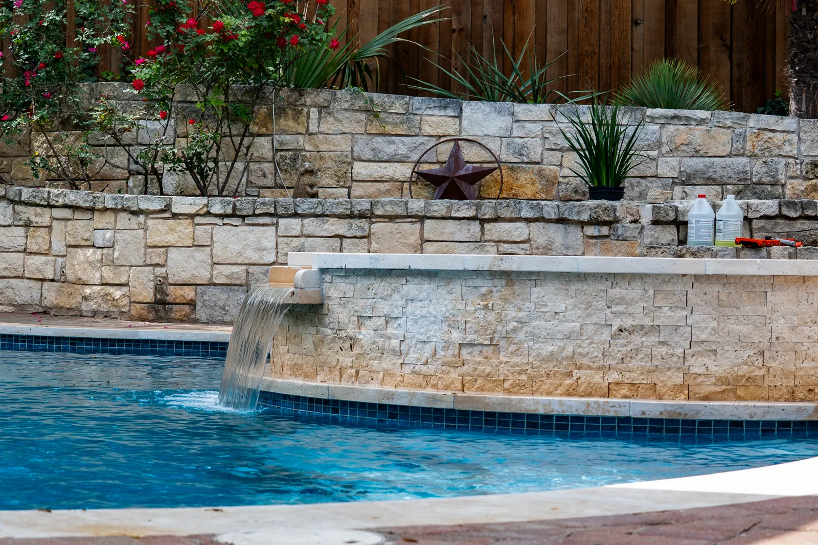 Water spilling over a limestone wall into a freeform pool