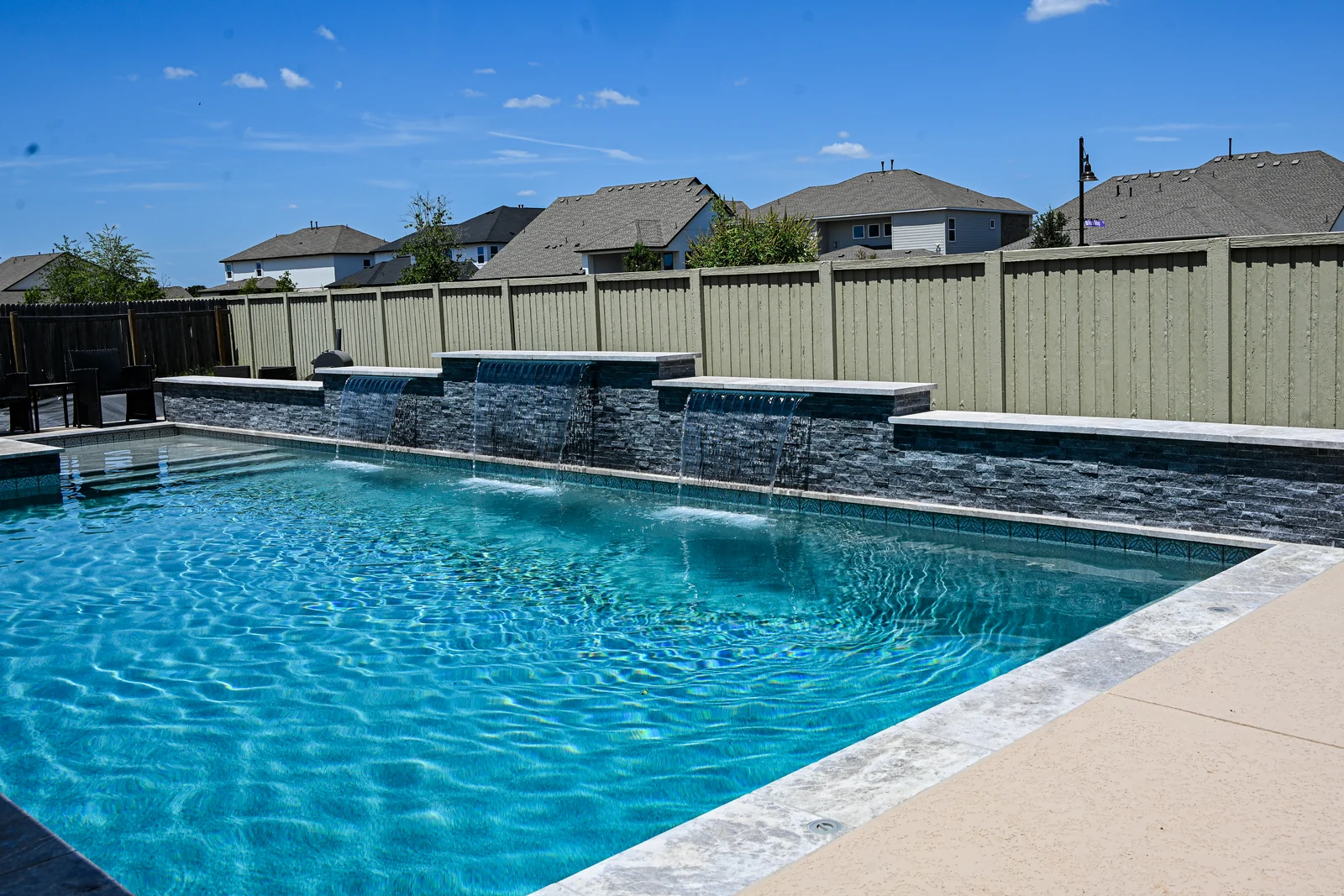 Rectangular pool running the length of a dark raised stone wall