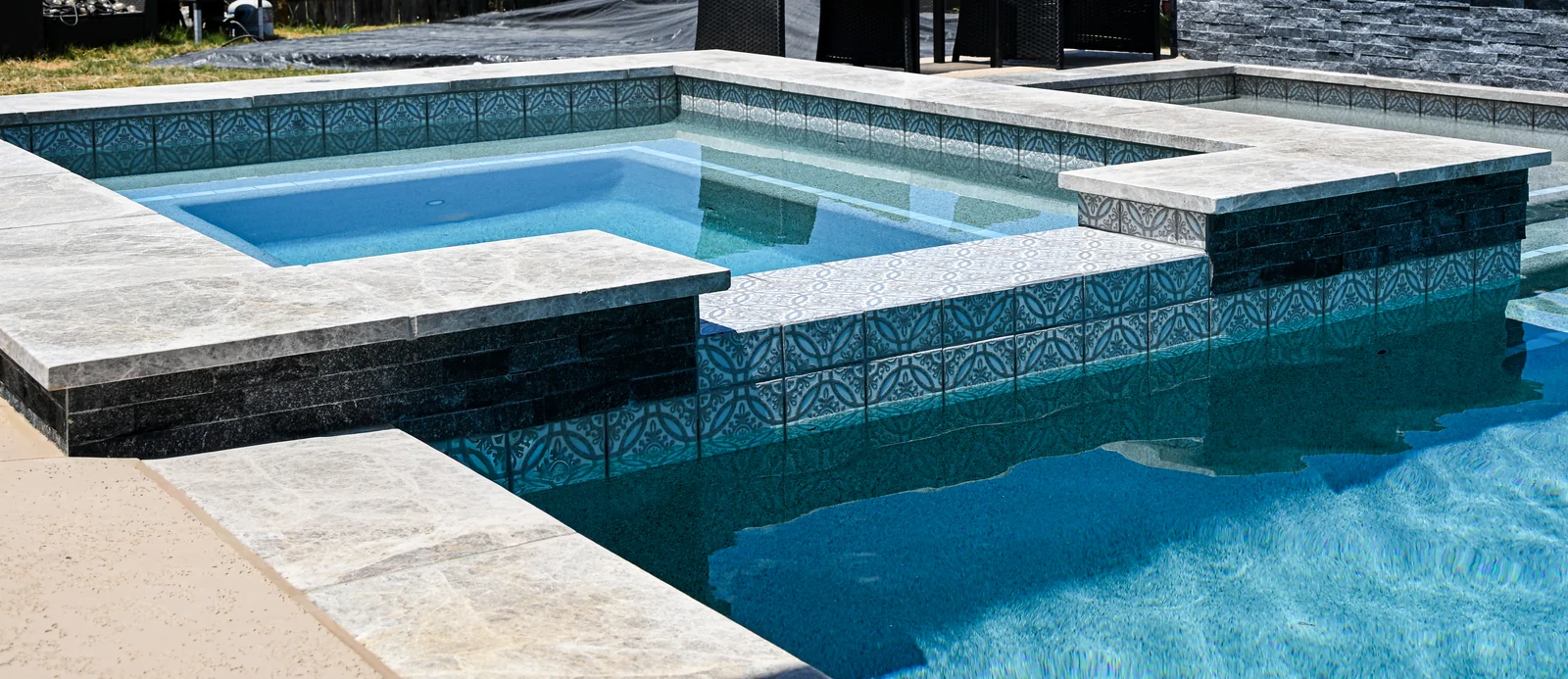 Spa set into a raised stacked-stone wall at the end of a pool