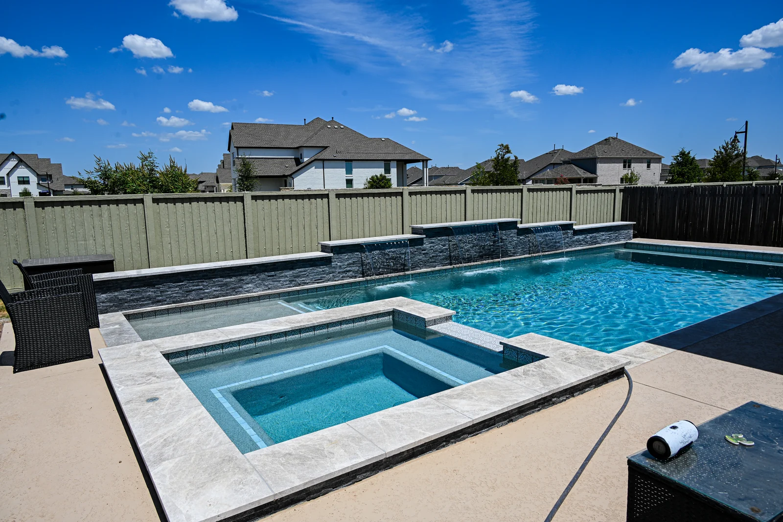 Square spa with travertine coping beside a rectangular pool