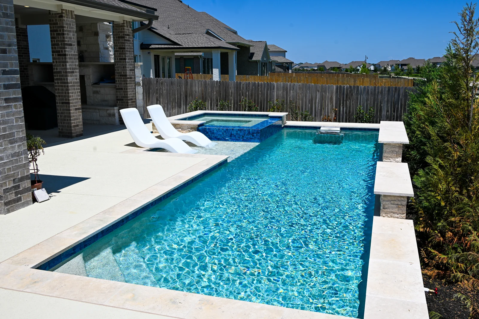 Geometric pool seen from a covered patio, loungers along the tanning ledge