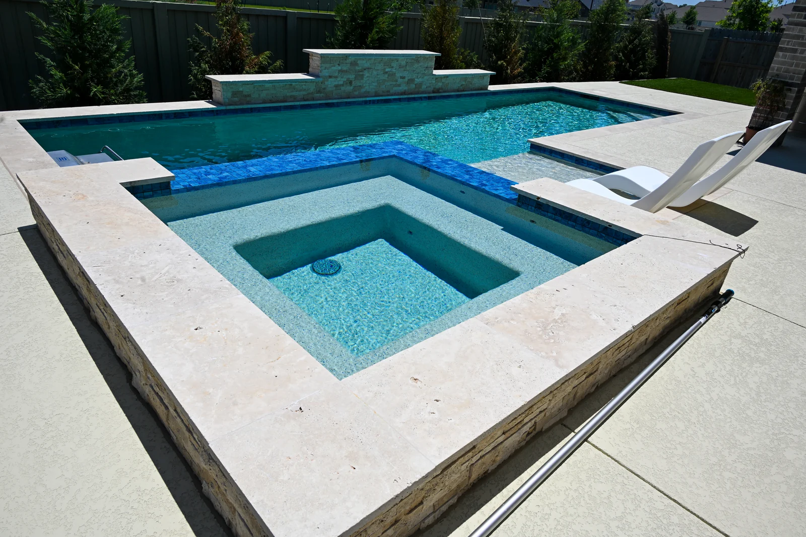 Square spa and adjoining tanning ledge finished in blue glass mosaic tile