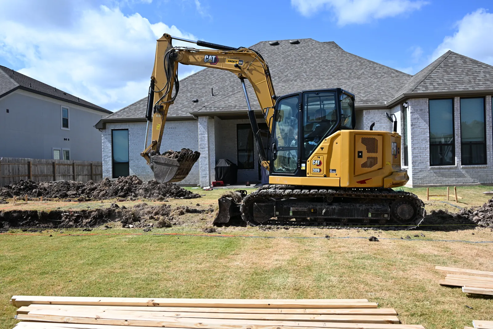 Excavator digging a pool in a new-construction backyard