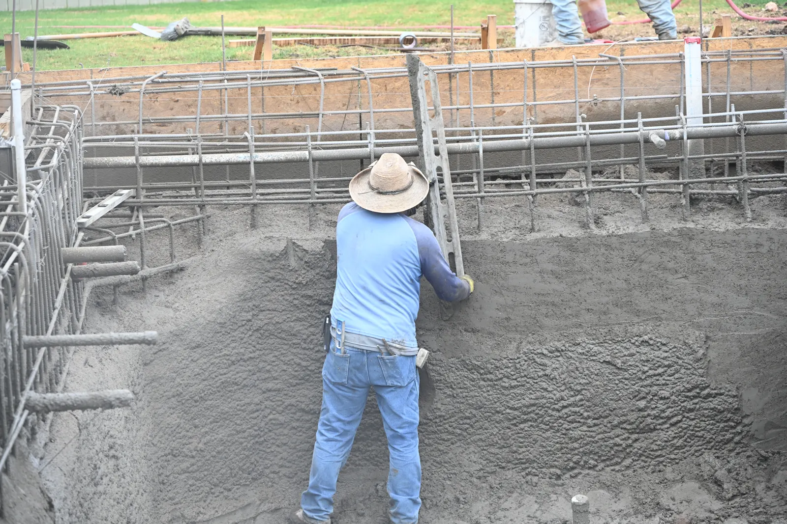 Nozzleman shooting gunite onto the wall of a pool shell