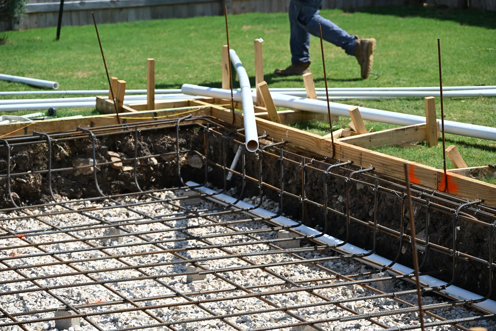 PVC plumbing runs laid over the rebar of a pool shell