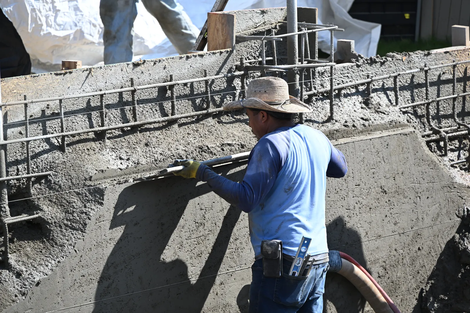 Crew member trowelling fresh gunite on a pool wall