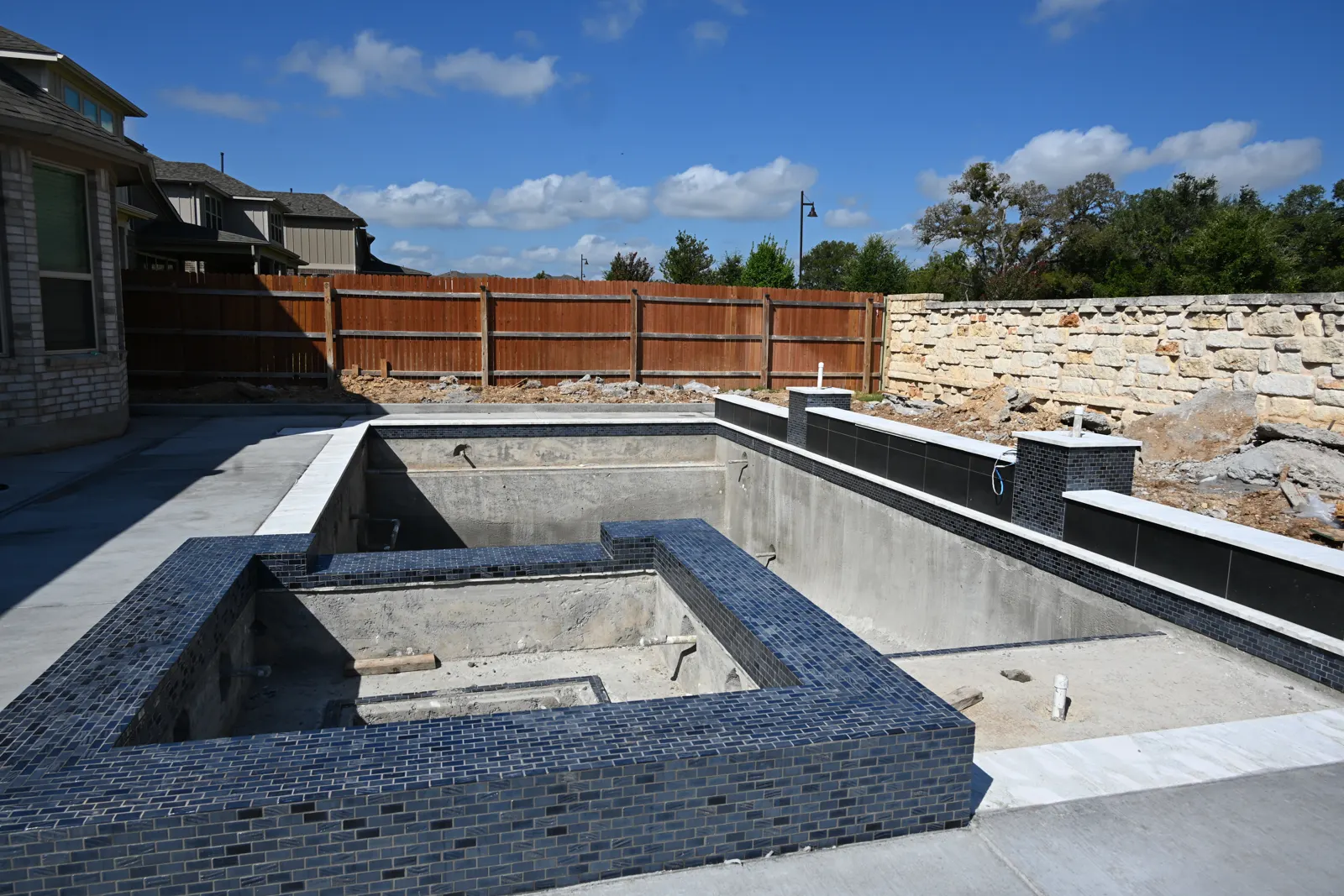 Gunite shell with dark tile going on the raised spa and wall