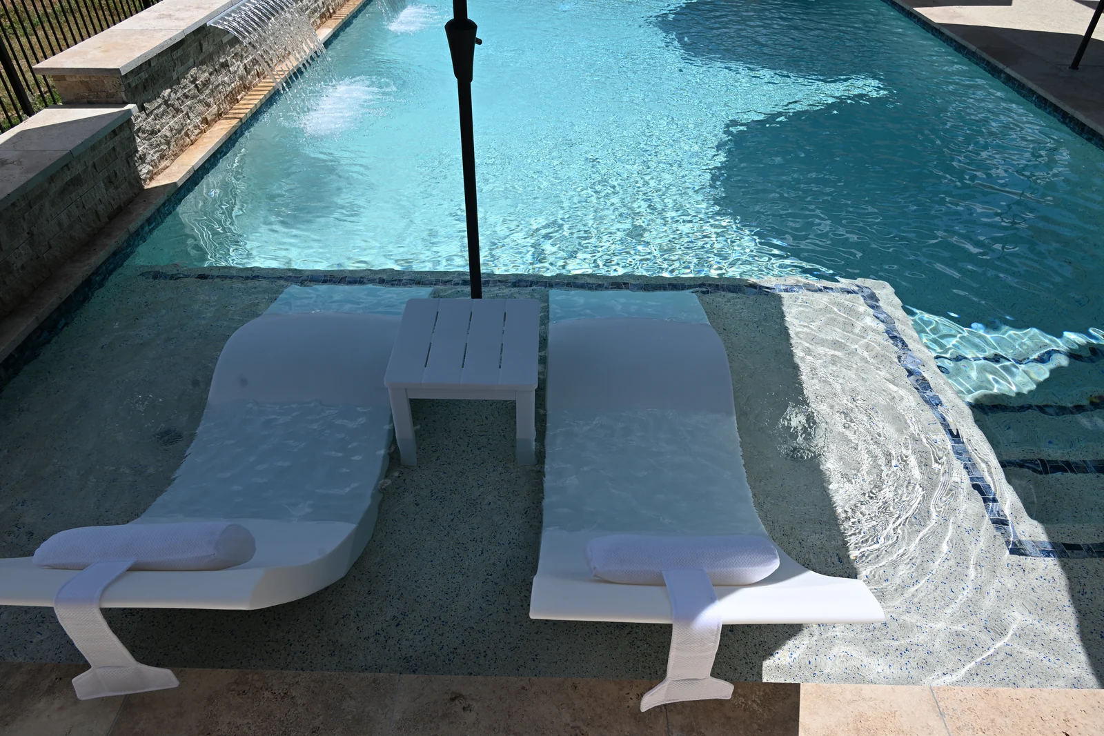 Two white in-water loungers set on a shallow tanning ledge