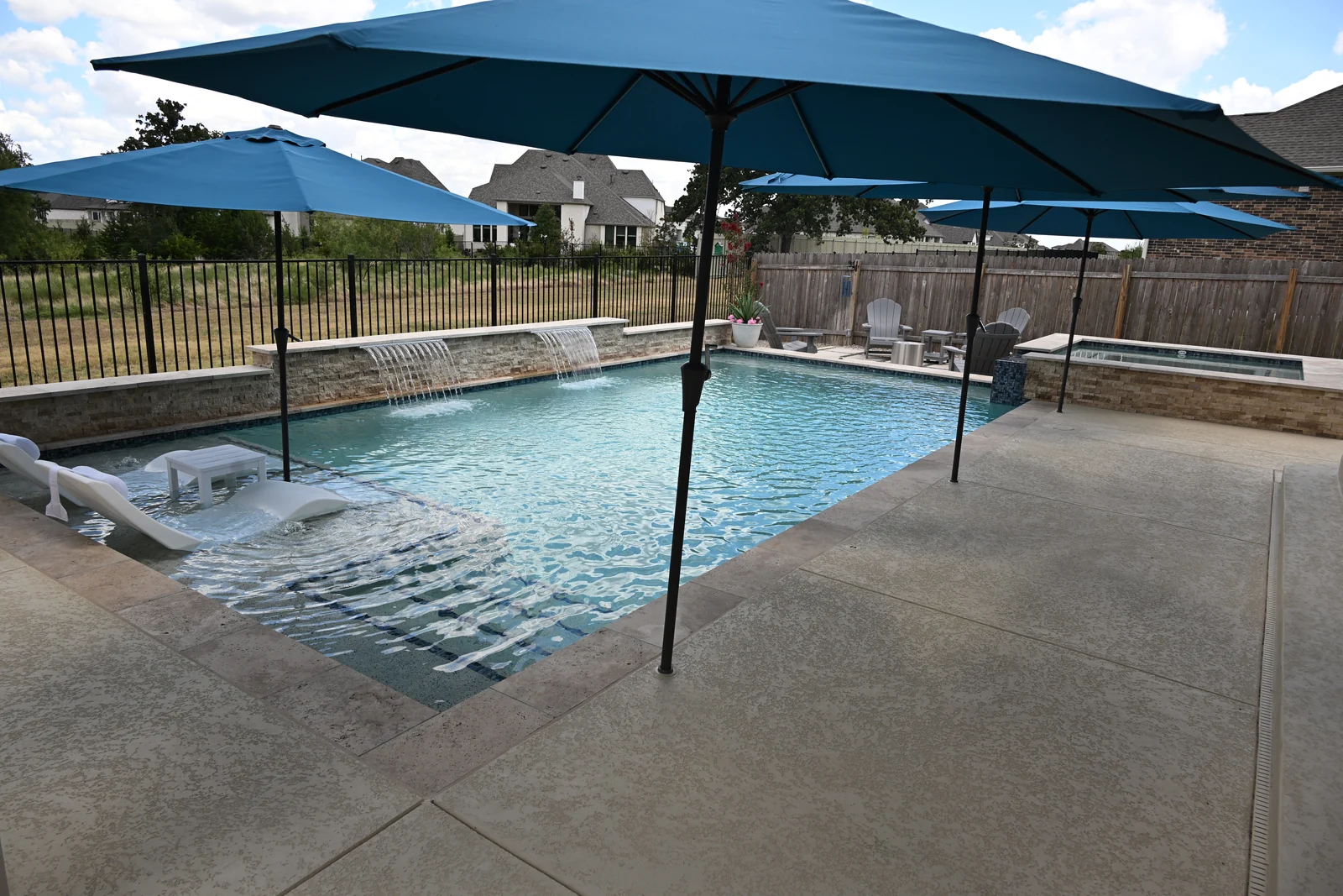 Long view down a rectangular pool across a travertine pool deck