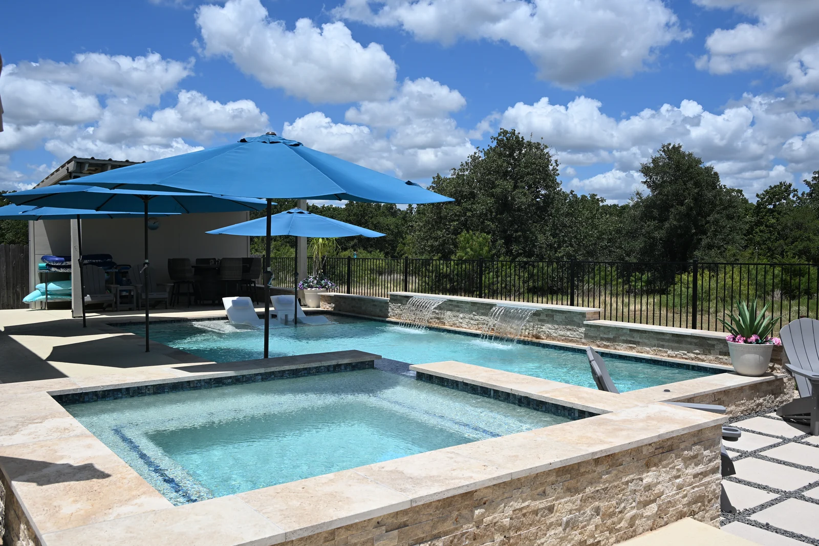Raised spa finished with travertine coping, spilling into the main pool