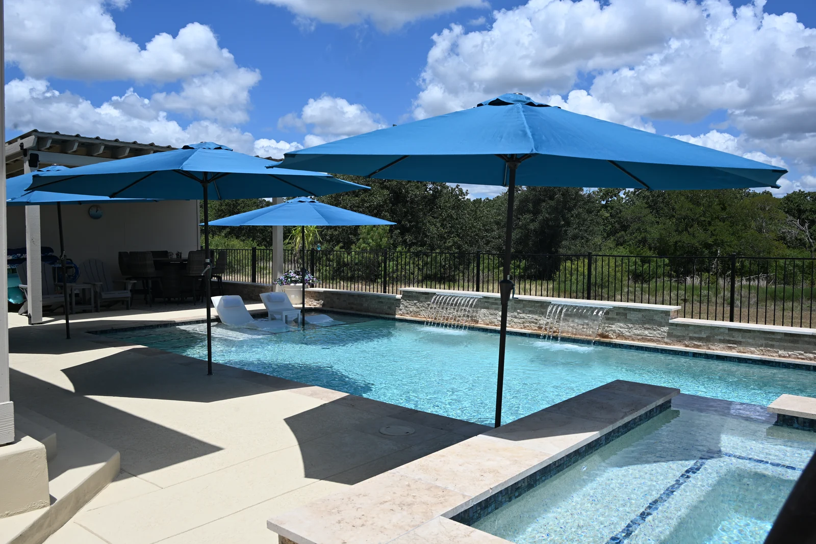 Blue patio umbrellas shading a tanning ledge at the shallow end of a pool